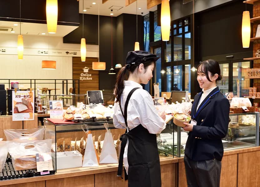 惣菜専門店で資材について打ち合わせをする店員と社員