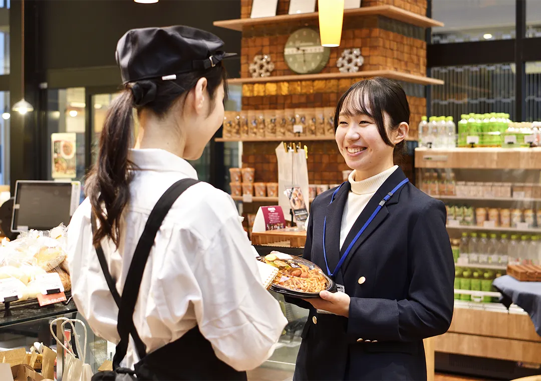 惣菜専門店で打ち合わせをする店員と社員